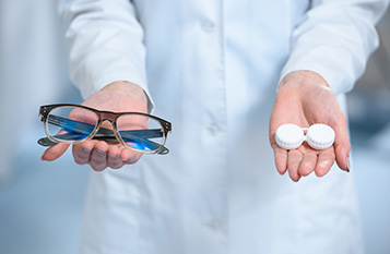 Óptico mostrando unas gafas y estuches de lentillas