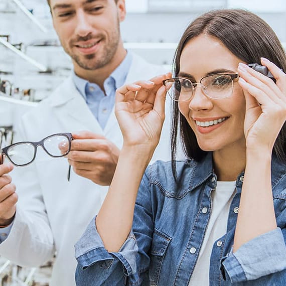 Clienta probándose unas gafas con ayuda de un óptico