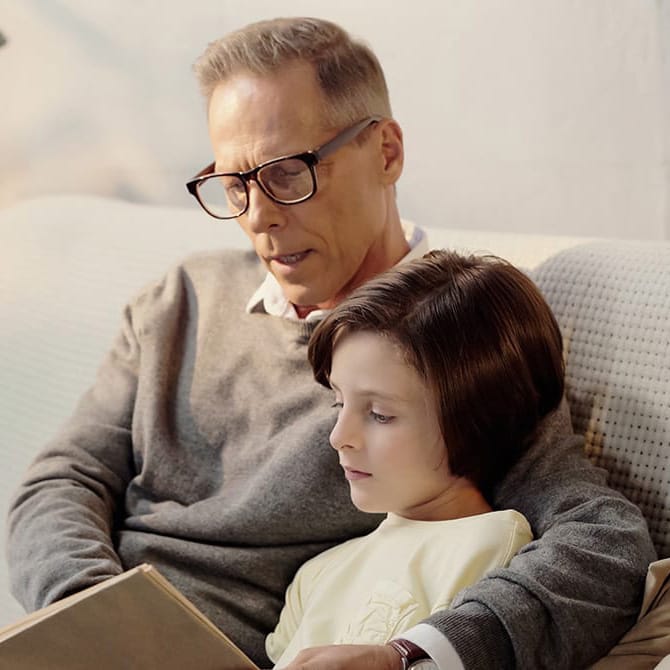 Hombre con gafas progresivas leyendo con su nieto
